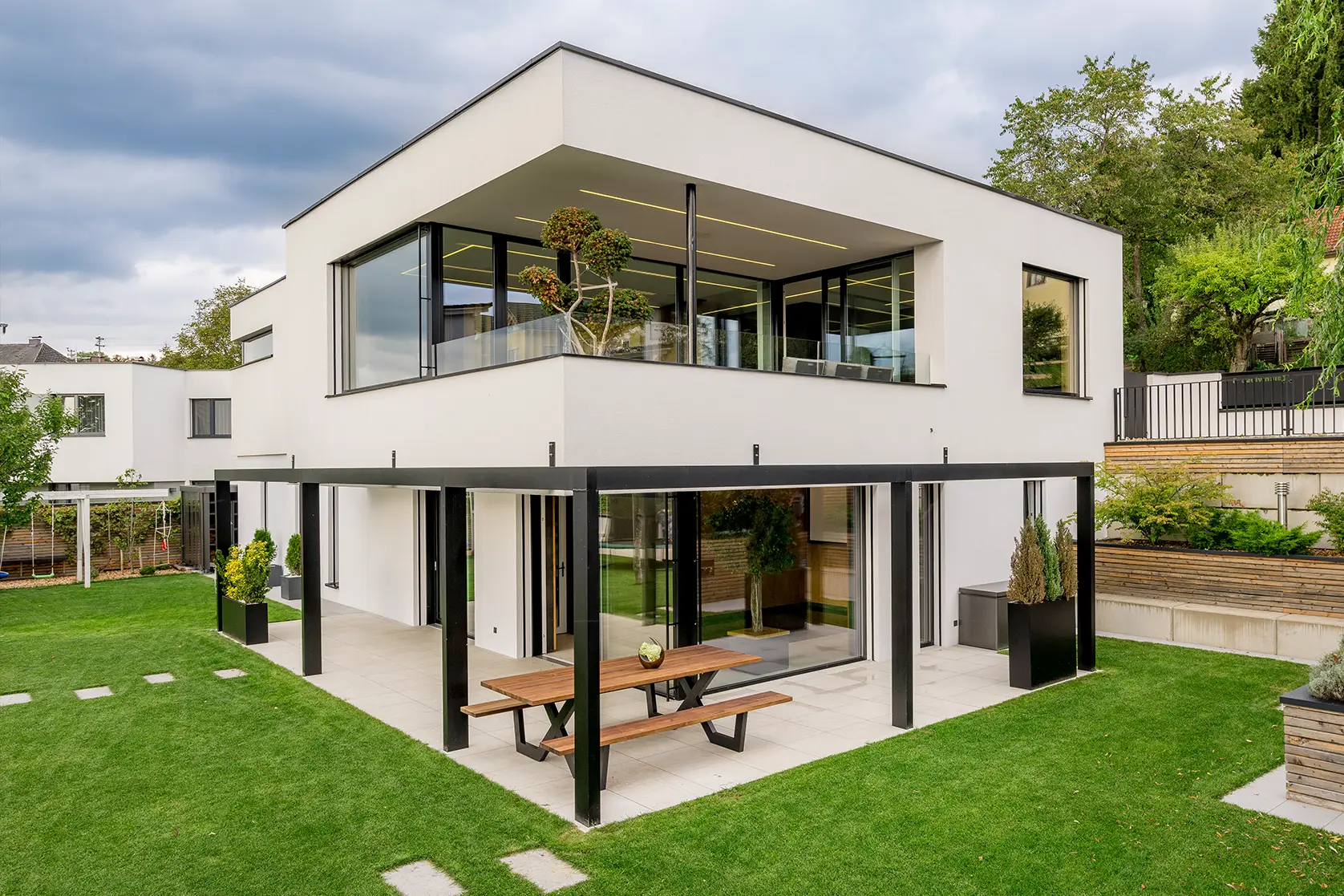 Zweistöckiges Haus mit Flachdach und überdachter Terrasse